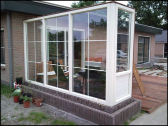 Kunststof windscherm/terras afscheiding op een plantenbak. Roeden in het glas.